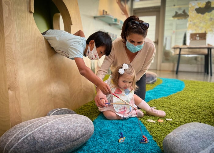 Family of 3 play with toy fishing poles in the Kidspace Museum Store
