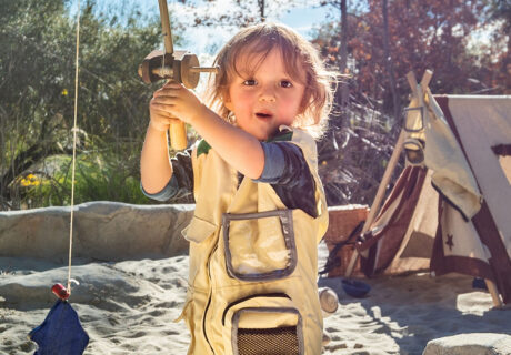 boy fishes with tent in background