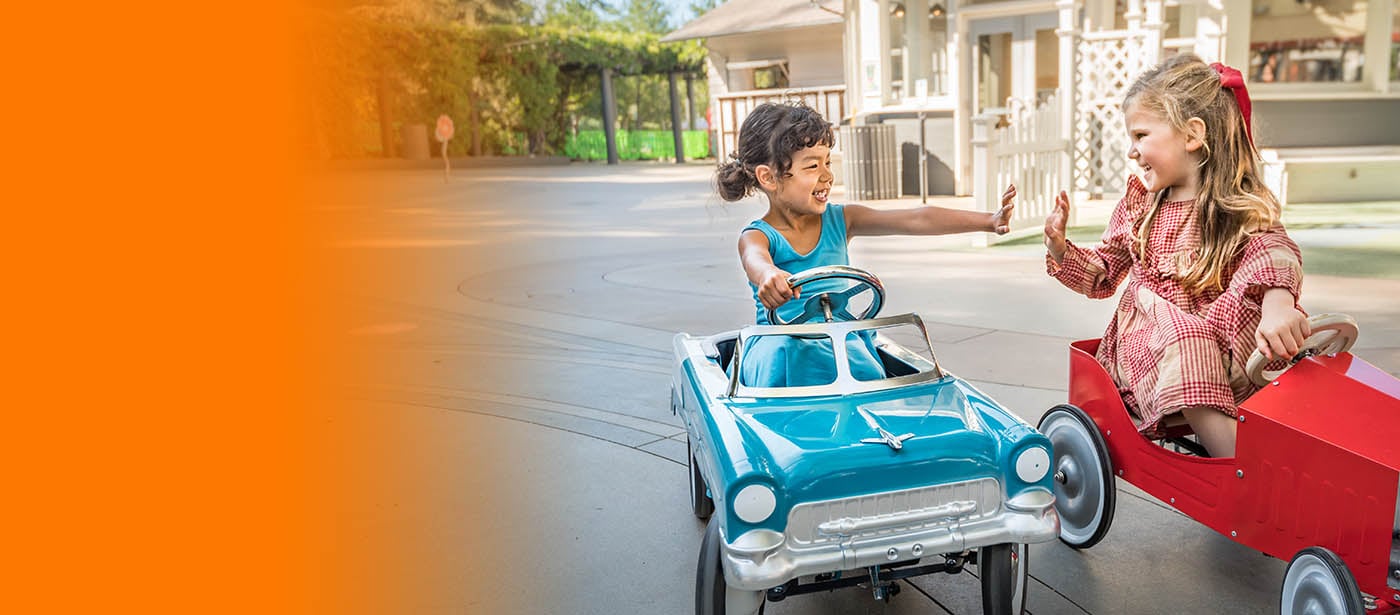 2 girls in toy cars high five