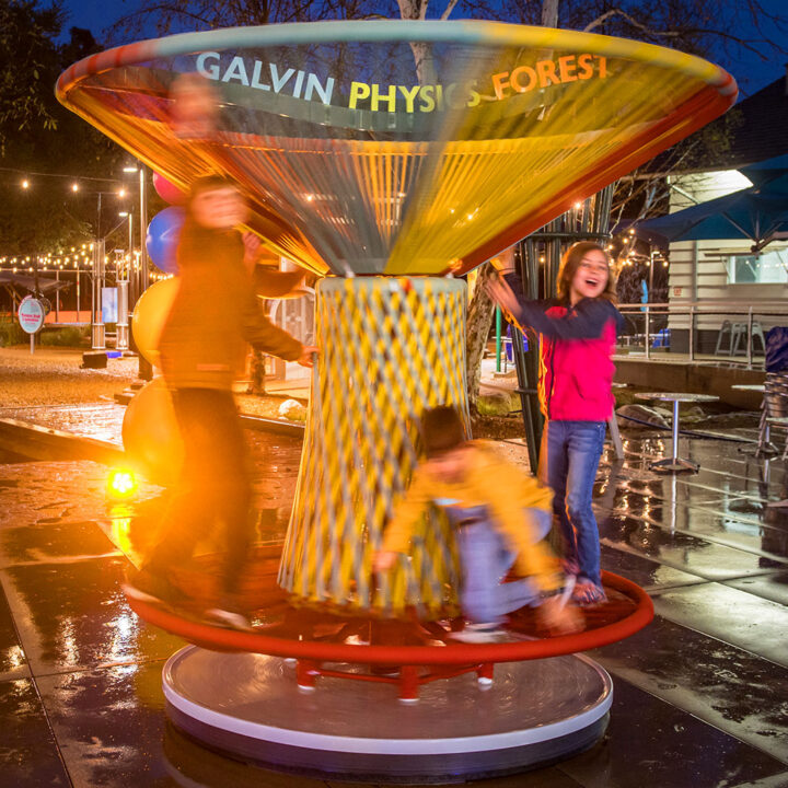 children play on colorful spinning outdoor top