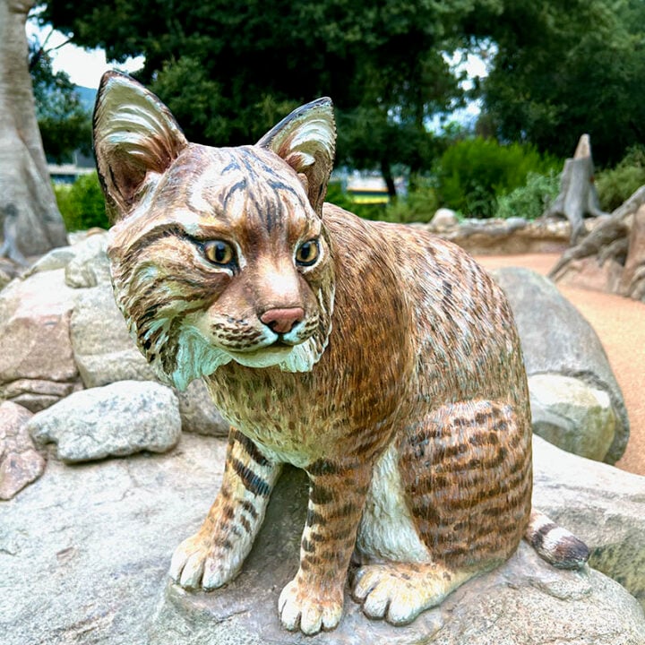 a statue of a bobcat sitting on a rock