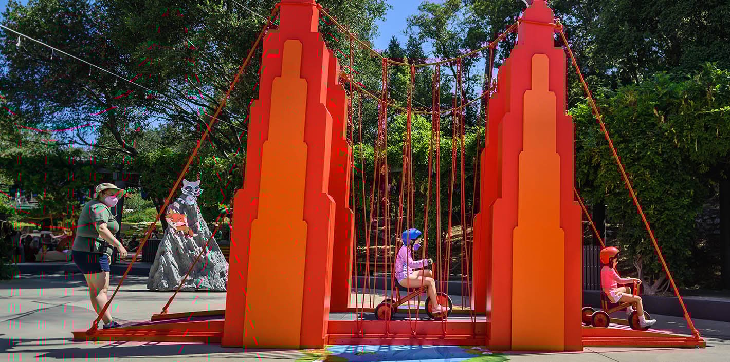 two children ride tricycles across a gigantic bridge