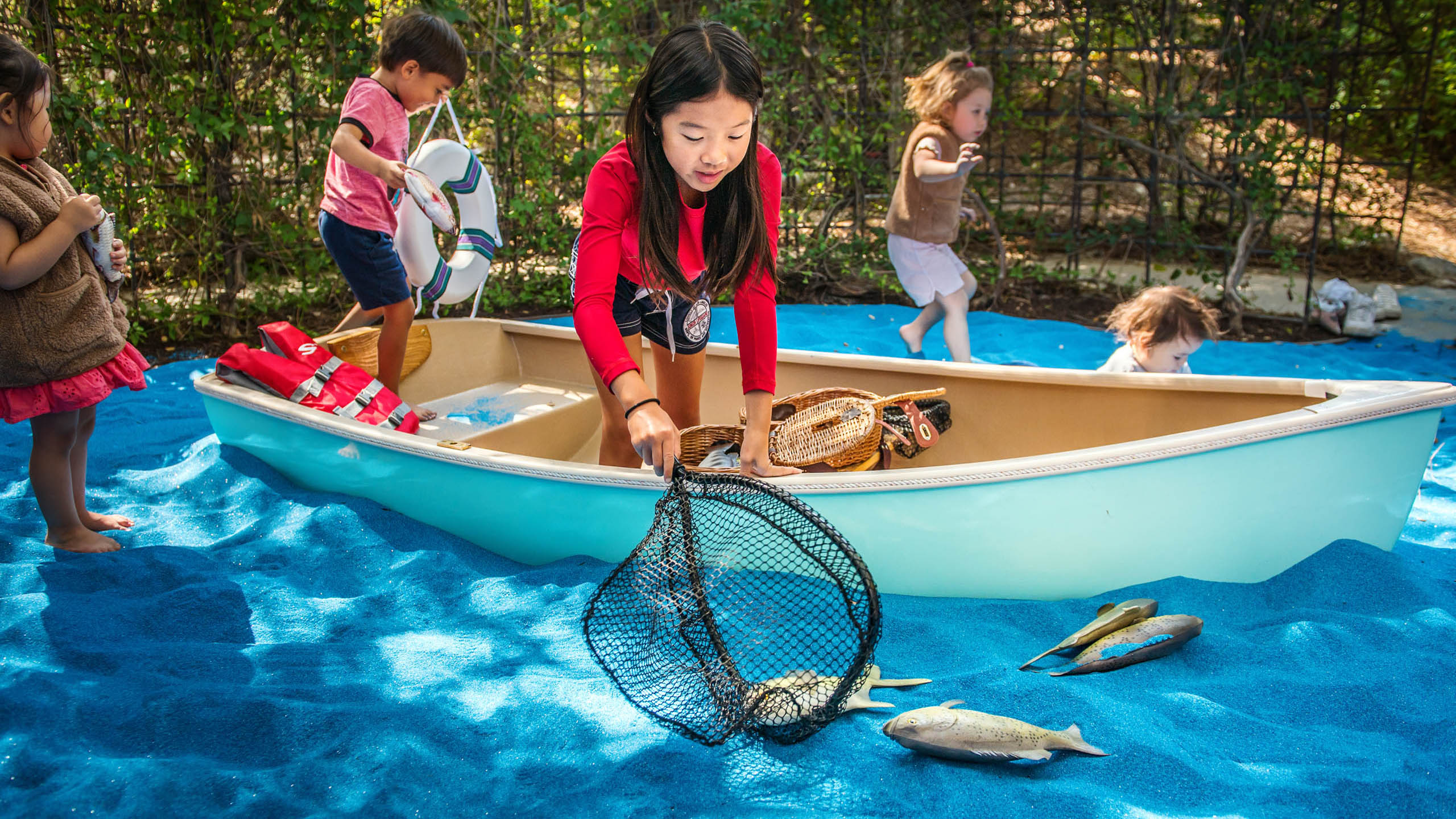 Children pretend to fish from a blue boat