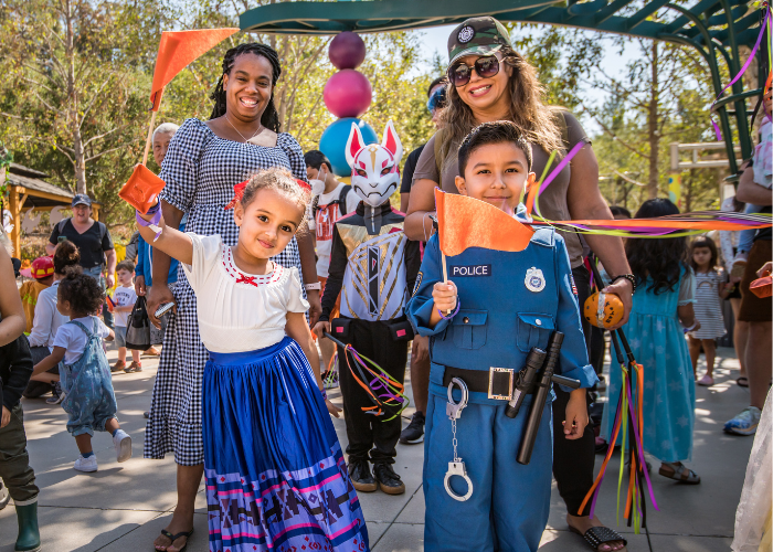 Children in costumes waving flags with parents looking on