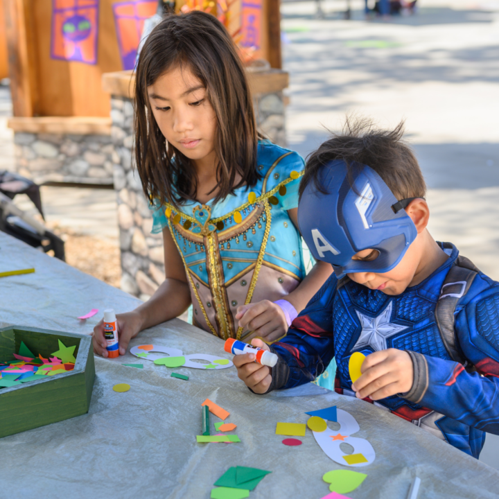 Dos niños disfrazados haciendo manualidades.