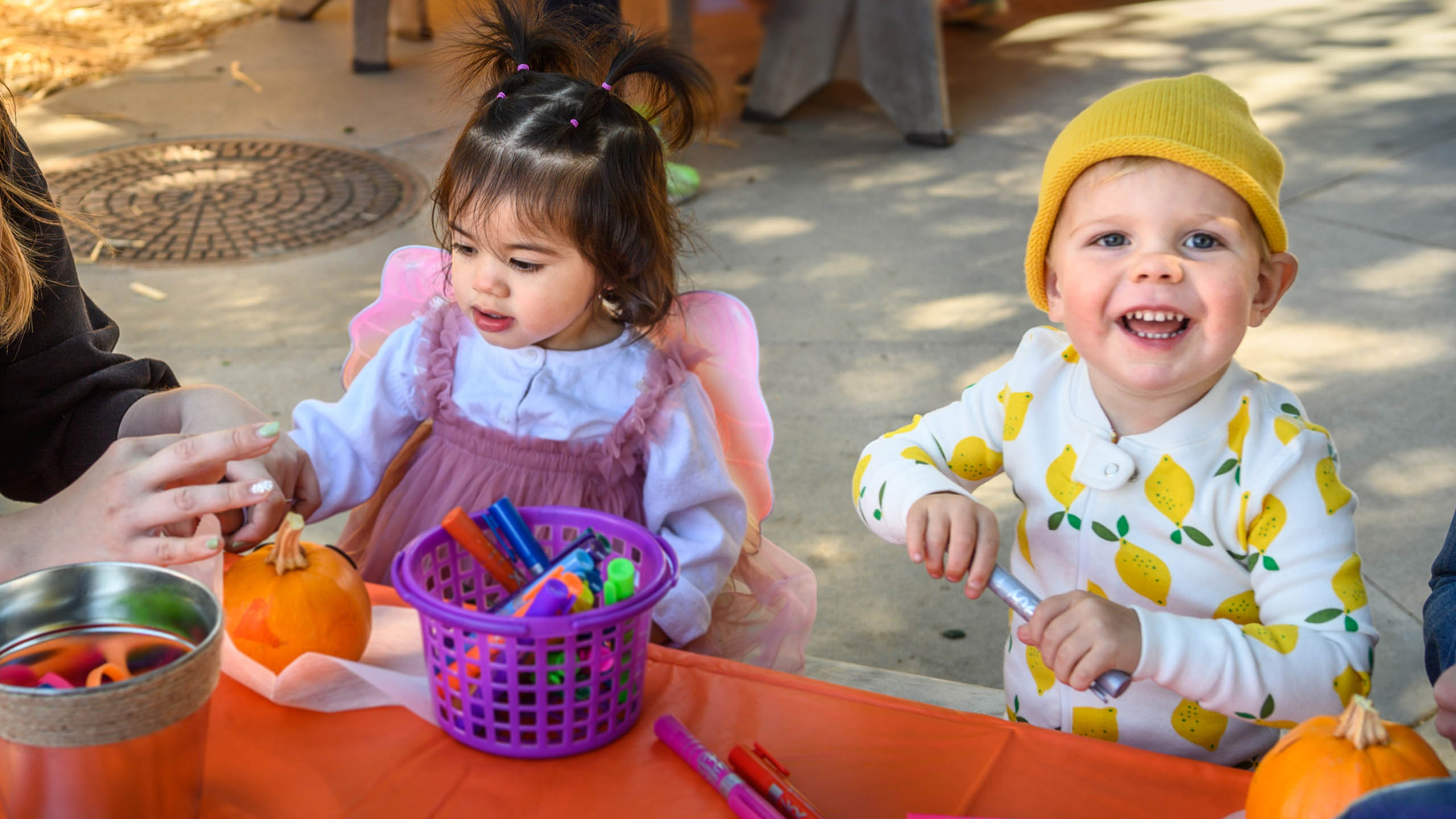 two toddlers decorate Halloween pumpkins