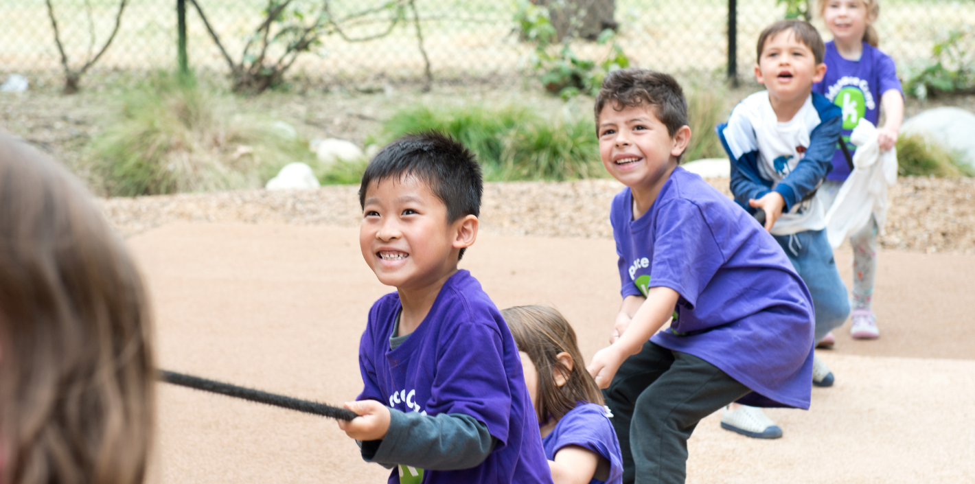 children in purple shirts playing tug of war