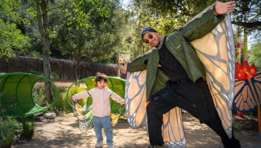 A man and his daughter with their arms spread out with butterfly wings on their backs.