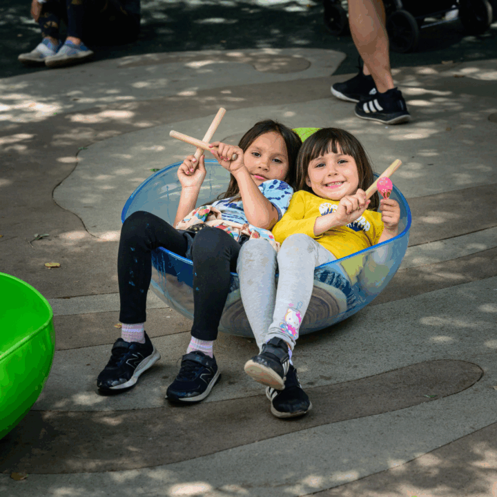 two children in bowl seating with instruments