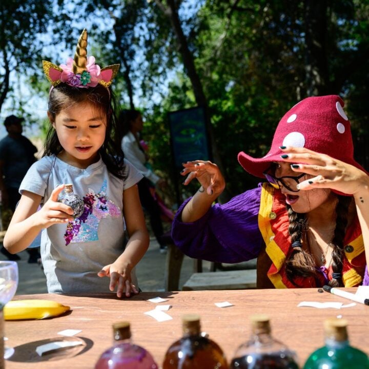 Child holds potion bottle while a garden fairy casts a spell on it
