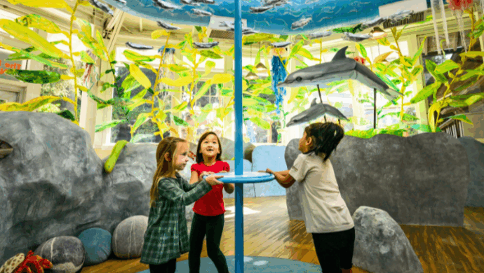 Children spin a school of fish made from plastic bottles
