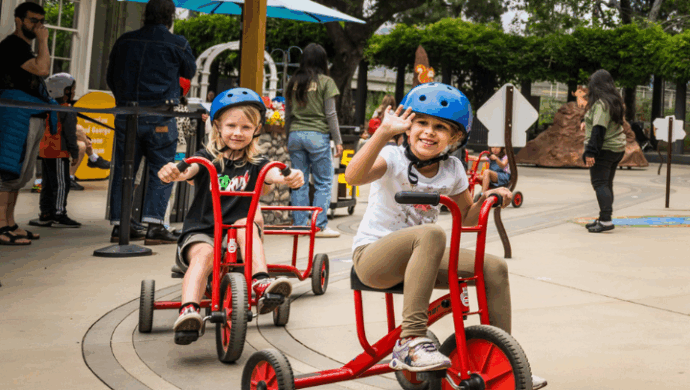 Child waves while riding a trike