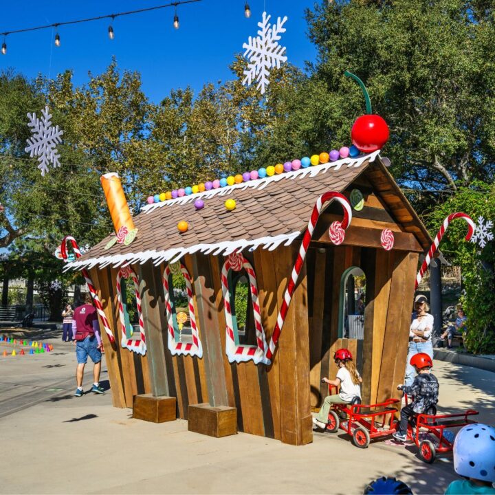 Kids riding trikes though a giant candy house