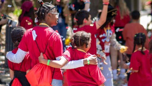 Three kids arm in arm at a celebration