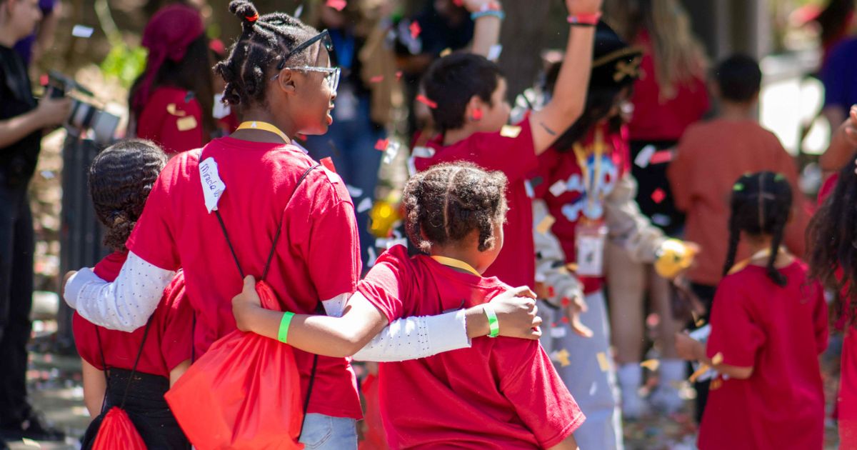 Three kids arm in arm at a celebration