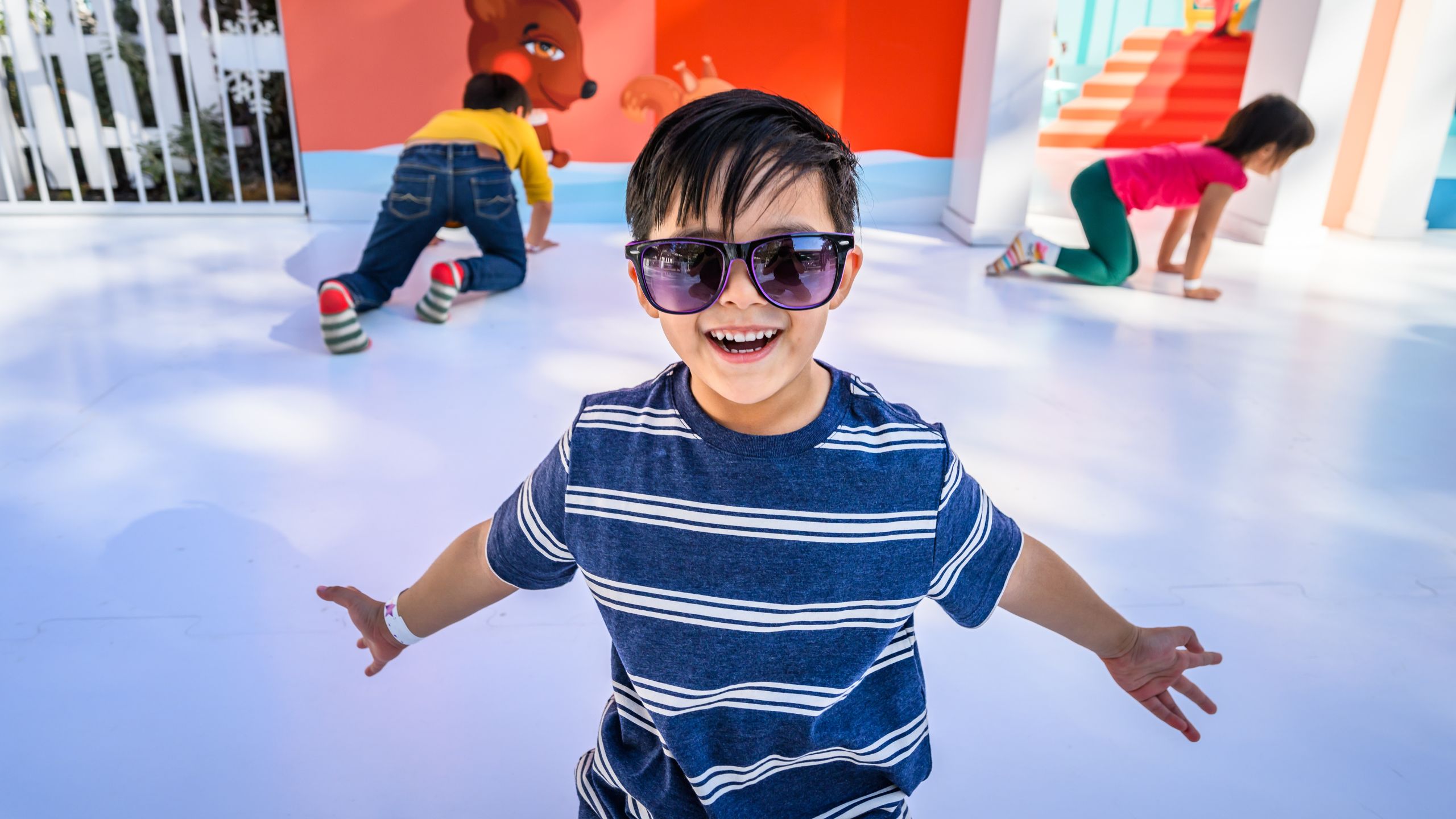 chid with sun glasses smiles at the camera on a sock skating rink