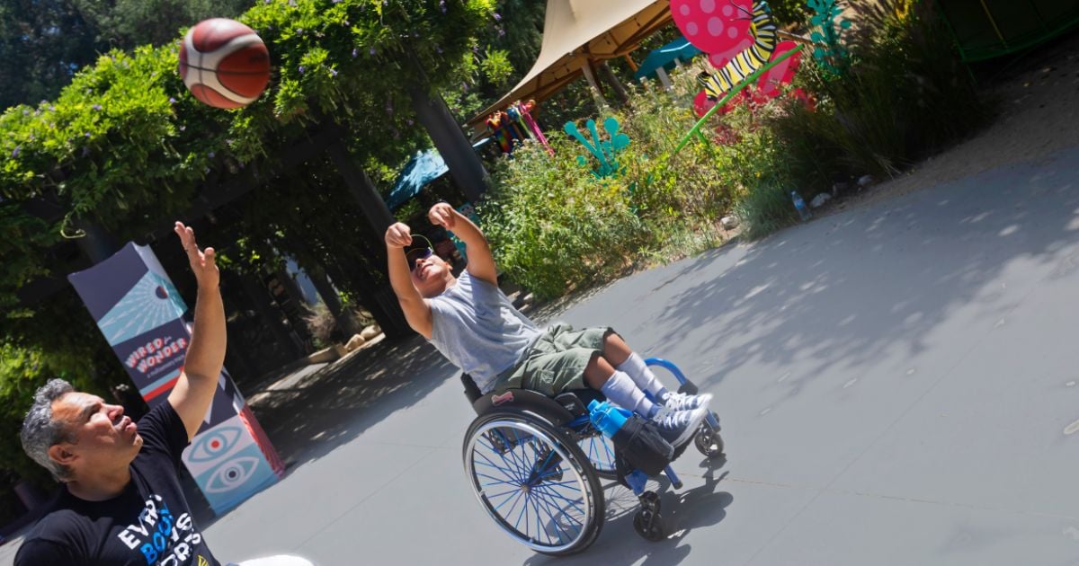 Child in wheel chair takes a shot with a basketball