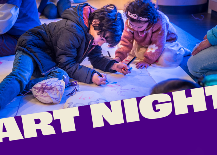 Two children drawing on a large paper mural