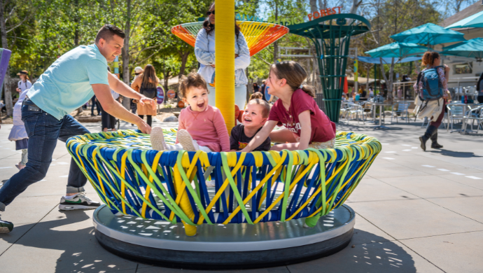 cheering kids get pushed on a spinning woven sculpture