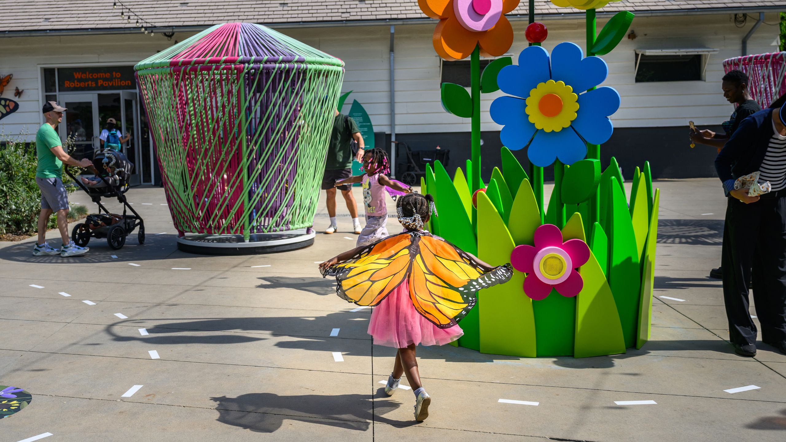 child flaps play butterfly wings near a giant flower pot