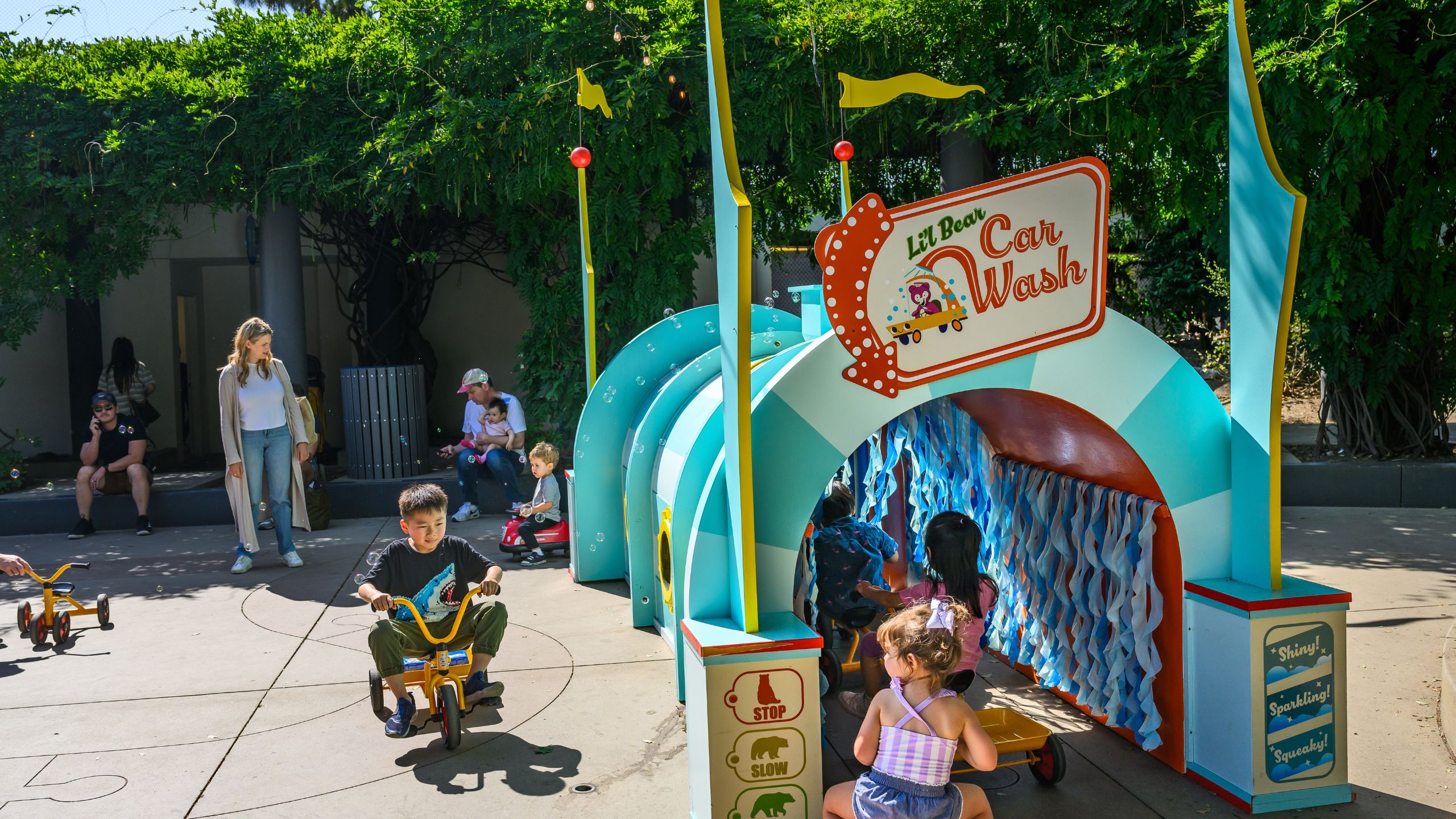 Children ride trikes through the lil' bear carwash