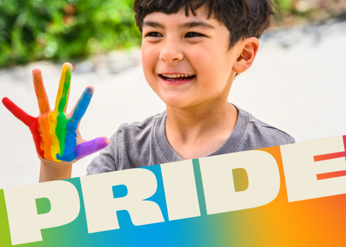 Smiling child holds up hand painted with a rainbow