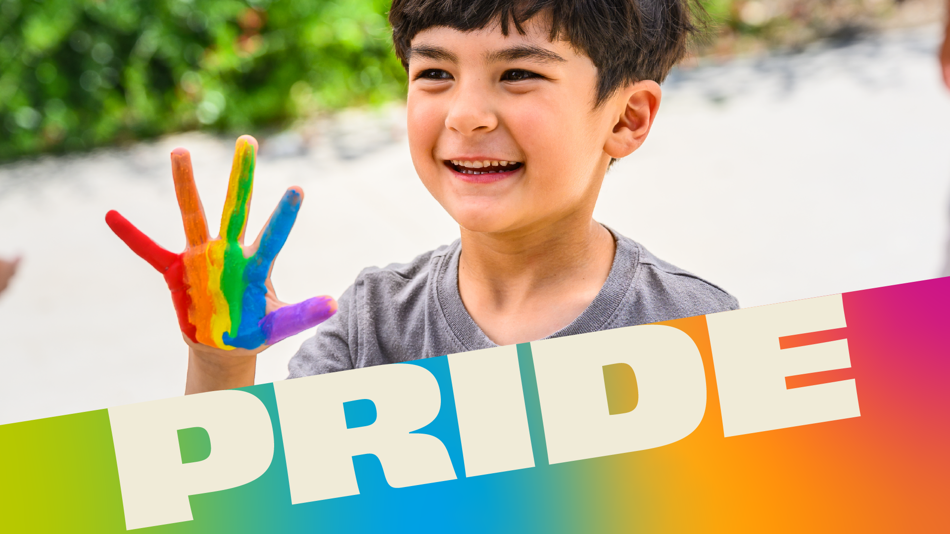 Smiling child holds up hand painted with a rainbow