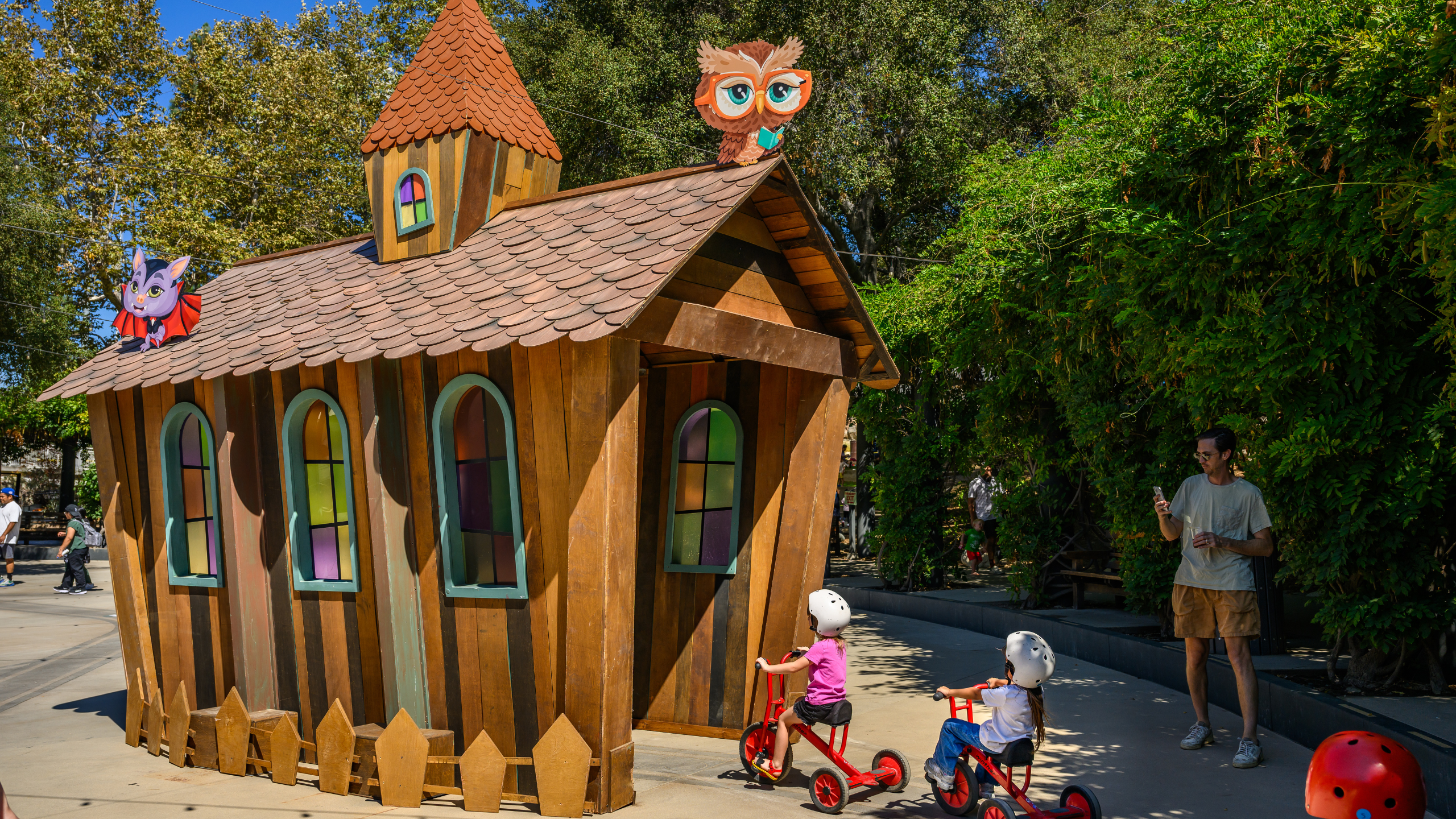 Children ride trikes through a halloween house tunnel